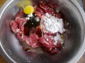 牛肉切成条状，放入小苏打拌匀，腌制10分钟后，再在碗里加入一个鸡蛋，玉米淀粉，蚝油，适量盐，用手抓制5分钟，使之粘稠。