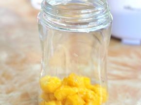 将芒果分成两半，一半切块，一半放入料理杯中。