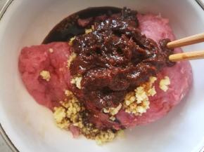 剁好的肉馅，加入姜末，生抽，老抽，盐，黑胡椒，豆瓣酱适量，提鲜。搅拌均匀后加点水，分次搅打进肉馅，完全上劲