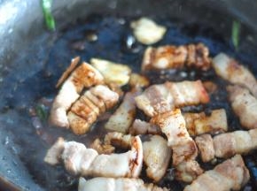 锅里倒少许油，放入五花肉煸炒，加入八角、葱、姜、蒜，老抽、料酒。