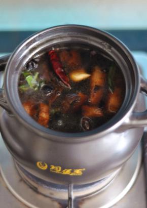 将五花肉移入砂锅中，加满水，放入干辣椒、香叶，水开后转小火煲煮一个小时。