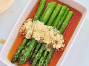 将蒜粒压成泥状，铺在芦笋上面。