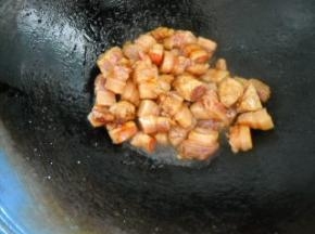 白糖炒至快拔丝时，下入肉块煸炒上色。