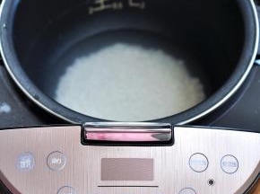将大米淘洗两遍后，放入电饭煲内，加入适量的水。