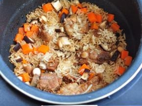 将生米、胡萝卜丁、香菇丁倒入电饭煲中，加适量的水，再用一个快煮饭程序，将米饭焖好。