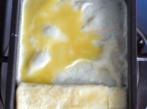 再继续倒一部分蛋液，由下至上将蛋卷卷起来。