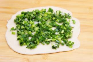 把面团擀薄，涂抹一层油，再铺上一层香葱；