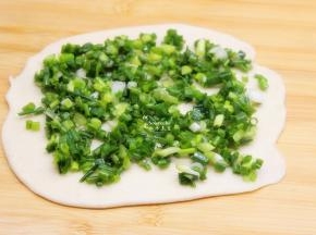 把面团擀薄，涂抹一层油，再铺上一层香葱；