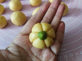 然后把抹茶小面丁整理成水滴状，粘一点水组装在南瓜饼干顶部中间的位置上