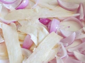 将杏鲍菇用削皮刀削成长条状，平铺在洋葱上。加少许油和盐，将蔬菜拌匀。