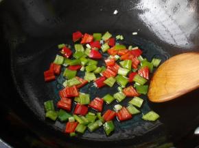 锅中留少许底油，加入青、红椒和葱段炒香