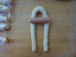 取一根长条面坯，卷成u形，放上玉米肠。