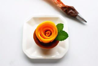 芒果花摆好后，在适合的位置挤出少许巧克力豆沙，插上薄荷叶装饰即可。