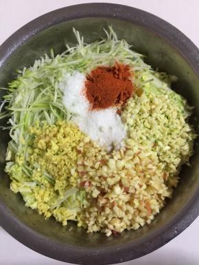 挤干水份的白菜中加入姜末，蒜末，苹果粒，萝卜丝，再加入味精和白糖15克，盐和辣椒面10克！