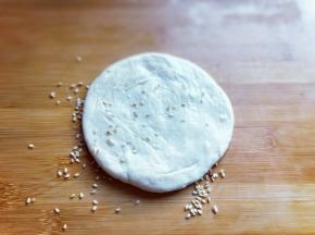 再面板上撒上少许熟白芝麻，把做的饼胚放在芝麻上压一下，使面团沾满芝麻。