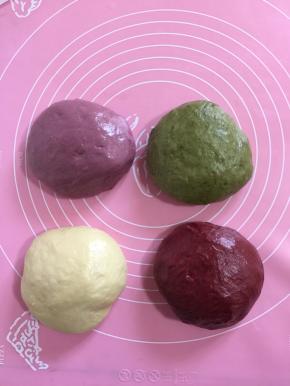 取出面团分成四份，每份面团280克！三个面团分别加入紫薯粉，抹茶粉，红曲粉手揉成面团后，分别放入面包机再揉面10分钟！