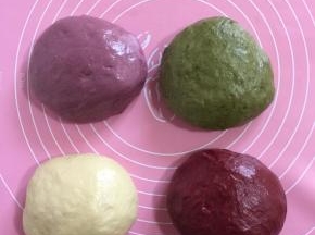 取出面团分成四份，每份面团280克！三个面团分别加入紫薯粉，抹茶粉，红曲粉手揉成面团后，分别放入面包机再揉面10分钟！