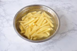 将土豆切成约1厘米左右宽的长条，放在水中加一勺盐清洗至无淀粉，尽量多换几次水。