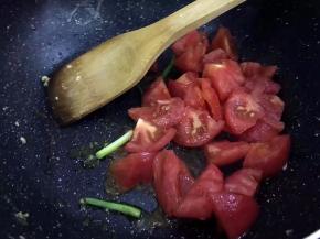 锅里放葱段爆香，将番茄切小块放入锅中