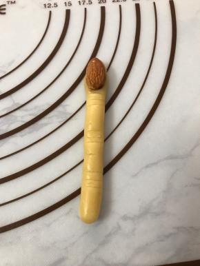 杏仁粘少许蛋液压在面团顶端，用线压出纹路。