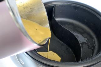 打好的红汤和纯豆浆分别倒入鸳鸯锅内