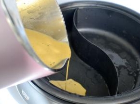 打好的红汤和纯豆浆分别倒入鸳鸯锅内