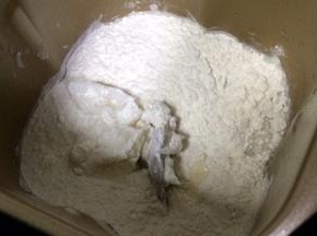 把油皮材料放入面包机桶内，按照水、糖粉、猪油，最后中筋面粉的顺序。启动面包机和面功能，时间设定为30分钟。