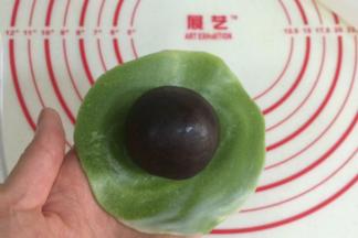 把擀开的面皮翻个面，有纹理的那面朝下，放上一枚馅料。