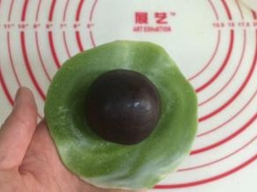 把擀开的面皮翻个面，有纹理的那面朝下，放上一枚馅料。
