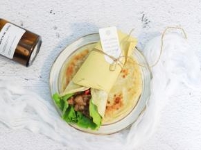 取一张饼，放入两片生菜，放入牛肉，卷起即可食用