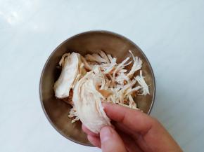 鸡胸变白捞出冲凉，顺着鸡丝纹路方向手撕成细丝。