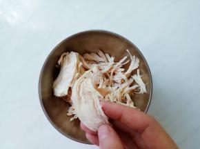 鸡胸变白捞出冲凉，顺着鸡丝纹路方向手撕成细丝。