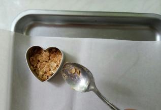 烤盘铺油纸，将模子一手按在油纸上，一手取一勺燕麦片填充在模子里。填充厚度半厘米左右即可，用勺子背儿尽量按紧实些。
