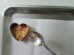 烤盘铺油纸，将模子一手按在油纸上，一手取一勺燕麦片填充在模子里。填充厚度半厘米左右即可，用勺子背儿尽量按紧实些。