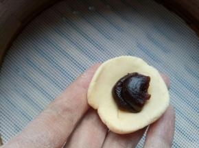 揪一块黄面，按扁，包一点豆沙馅，做成仔仔的头。