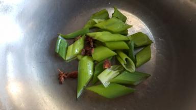 4.把葱切段和八角粒，放在锅的底部。