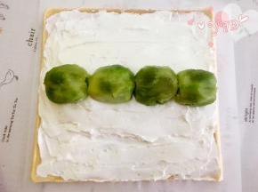 抹上淡奶油，中间高，两边薄，在中间奶油高的位置放上奇异果；