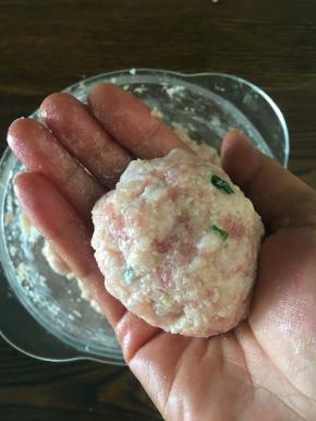 用手抓起合适大小的莲耦猪肉馅，用手左右交换团成丸子。