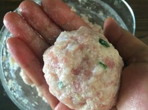 用手抓起合适大小的莲耦猪肉馅，用手左右交换团成丸子。