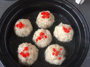 红椒撒在丸子上面盖上盖子，把辣椒煮熟。