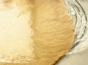 松弛好的面团，底部垫保鲜膜，表面也铺上保鲜膜，不然会黏。擀成半厘米厚的均匀片状。