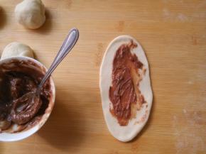 将一个面剂以中间为轴，先擀下面，再擀上面。擀成牛舌状，涂抹一层花生酱。