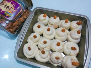 发酵好后，从烤箱取出烤盘。每个面剂表面按上一粒巴旦木。