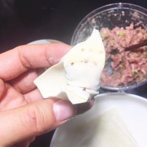 包好的云吞一边角用筷子沾一点水。