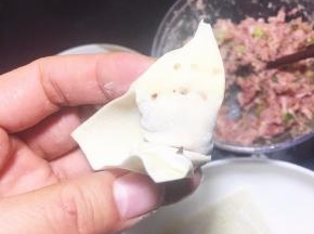 包好的云吞一边角用筷子沾一点水。