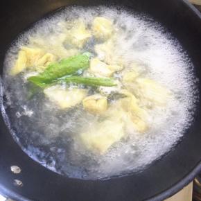 云吞煮到浮起，点一小碗冷水，再次把水煮开，放青菜煮熟。