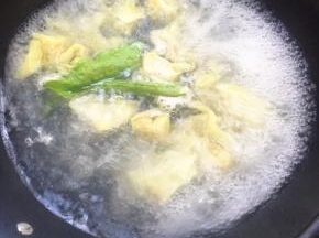 云吞煮到浮起，点一小碗冷水，再次把水煮开，放青菜煮熟。