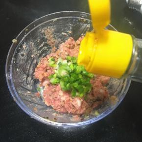 剁好的肉抹加入葱花，胡椒粉，盐，香油，半只蛋清，用力搅打起劲。