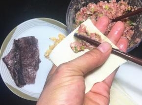 用一根筷子挑少许肉末，放在云吞皮的一角。