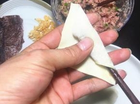 用筷子和拇指的配合把云吞皮往上包。